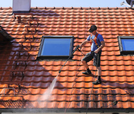 Worker is cleaning the roof and rainwater gutter with high pressure.